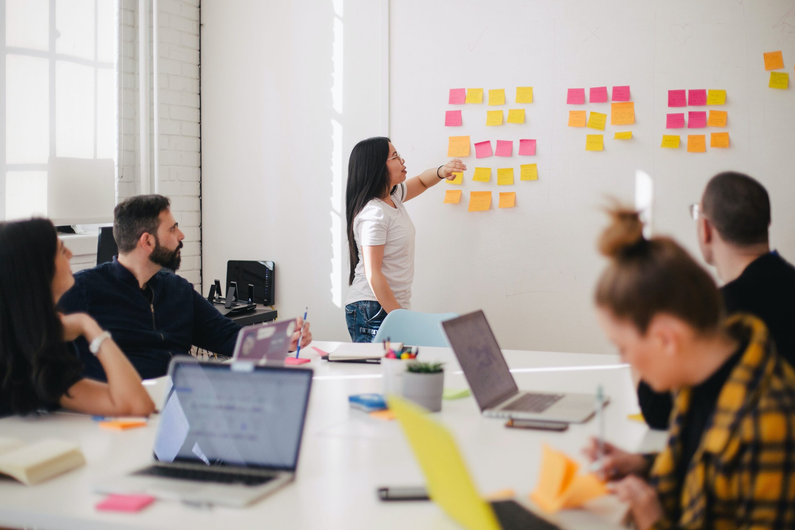 Woman placing sticky notes on a wall in a meeting